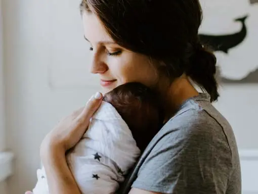 Ein Au-pair in Deutschland hält liebevoll ein Baby in den Armen.